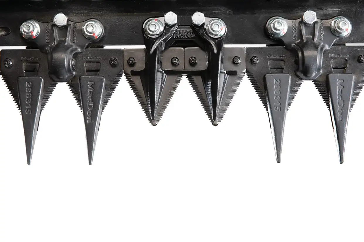 Case IH close-up of industrial metal cutting blades with sharp, triangular teeth and bolts against a white background. 