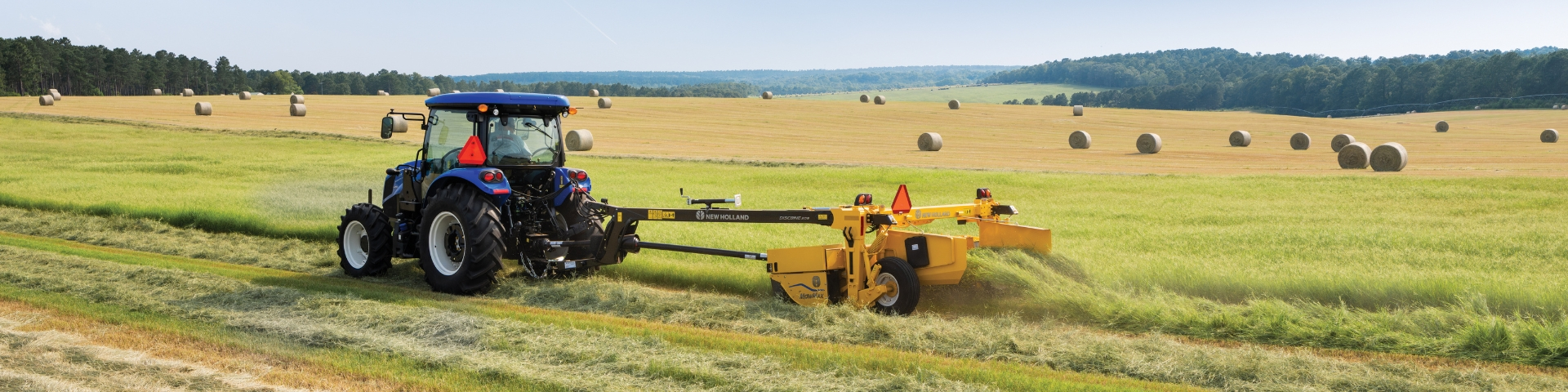 Blue tractor mowing hay.