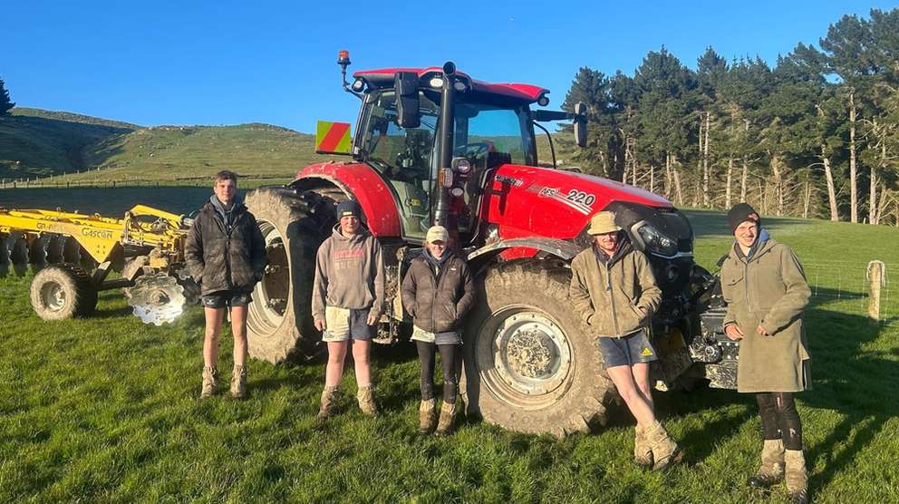 Red Case IH tractor i field with people around it