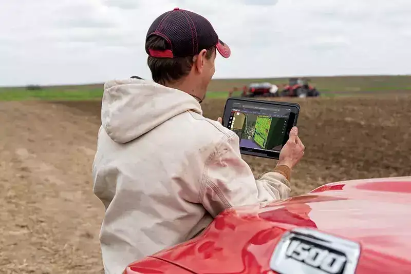 Farmer reviews his Field Ops telematics data on a tablet in a field.