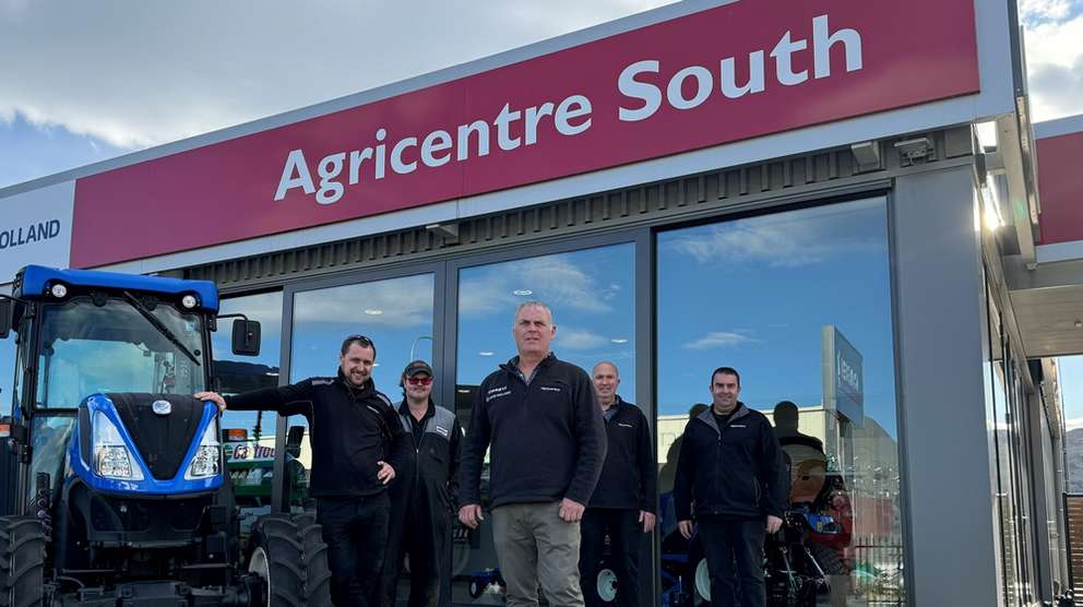 New Holland dealership staff standing in front of dealership signage