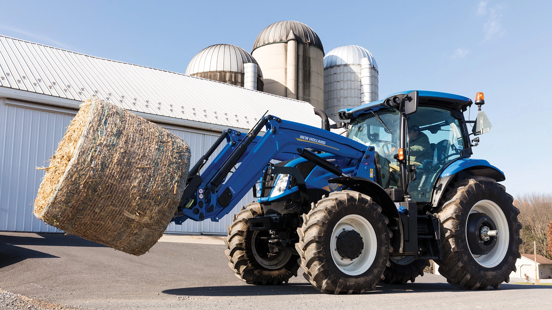 T6 Series tractor lifts a bale