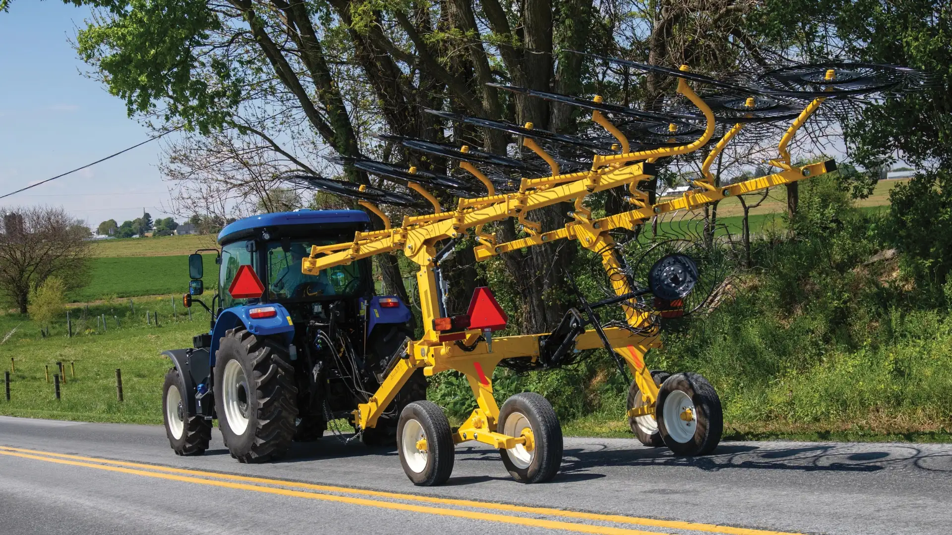 WorkMaster tractor pulling hay rake in on road.