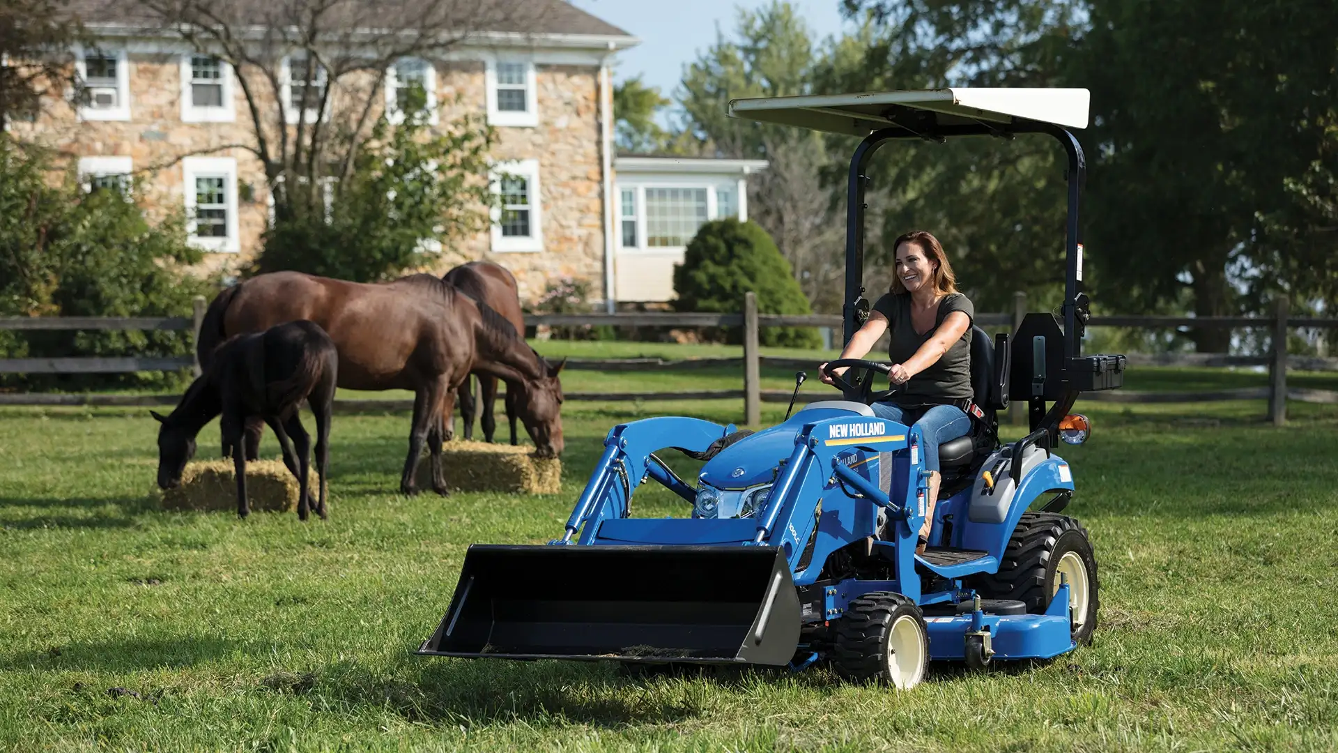 Woman operates WORKMASTER 25S tractor with a front loader