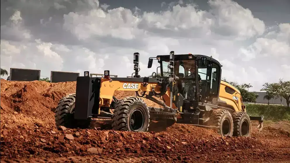 foto ao ar livre, com destaque para uma motoniveladora da Case Construction trabalhando.