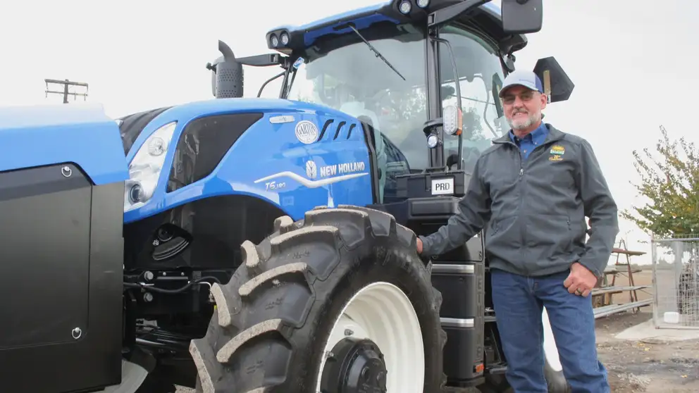 Man stands next to New Holland T6 tractor.