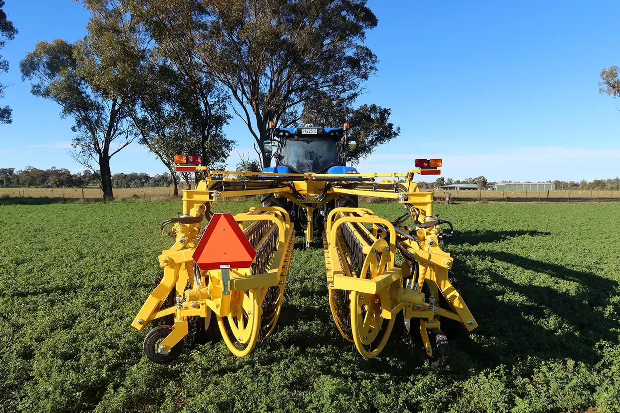 New Holland rolabar rake, roller bar working in field with New Holland tractor in Australia