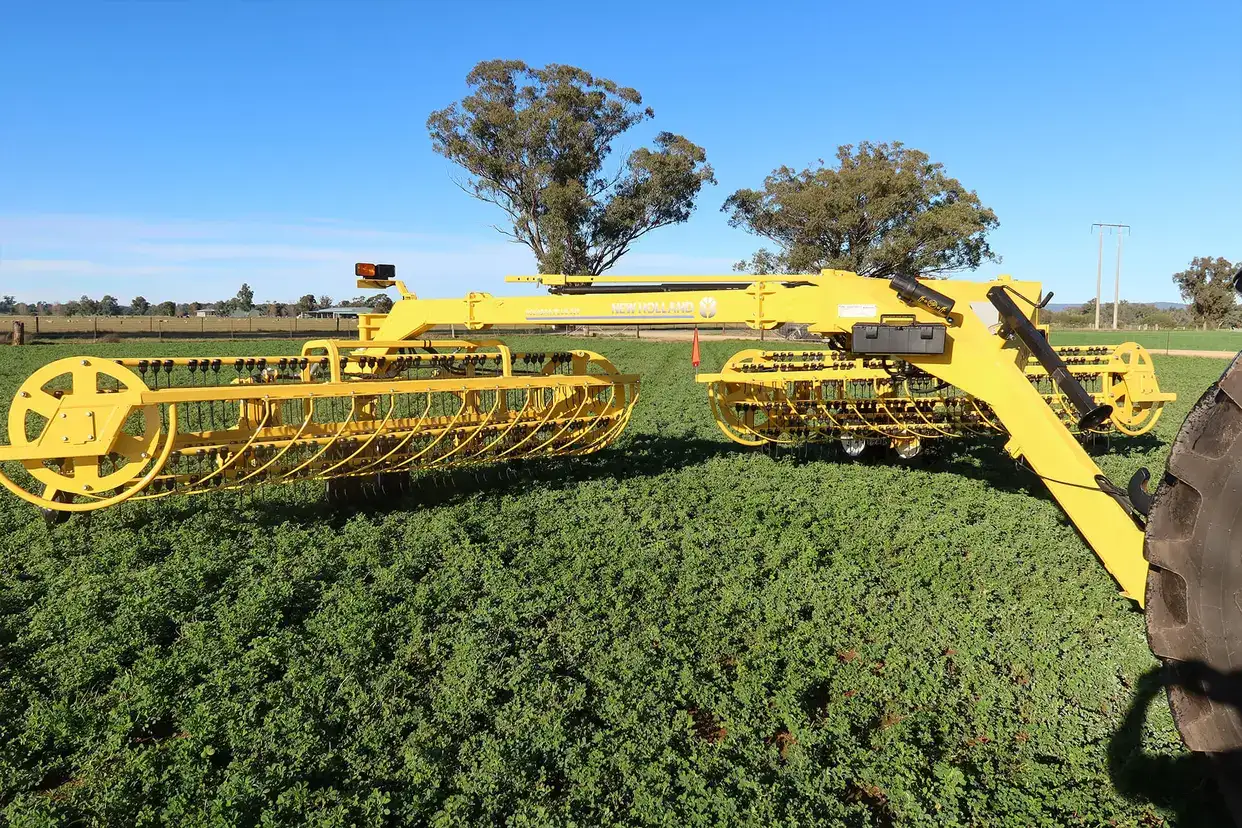 New Holland rolabar rake, roller bar working in field with New Holland tractor in Australia