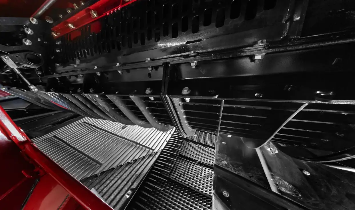 Interior view of a combine showing the cleaning system with sieves and airflow components designed for grain separation.