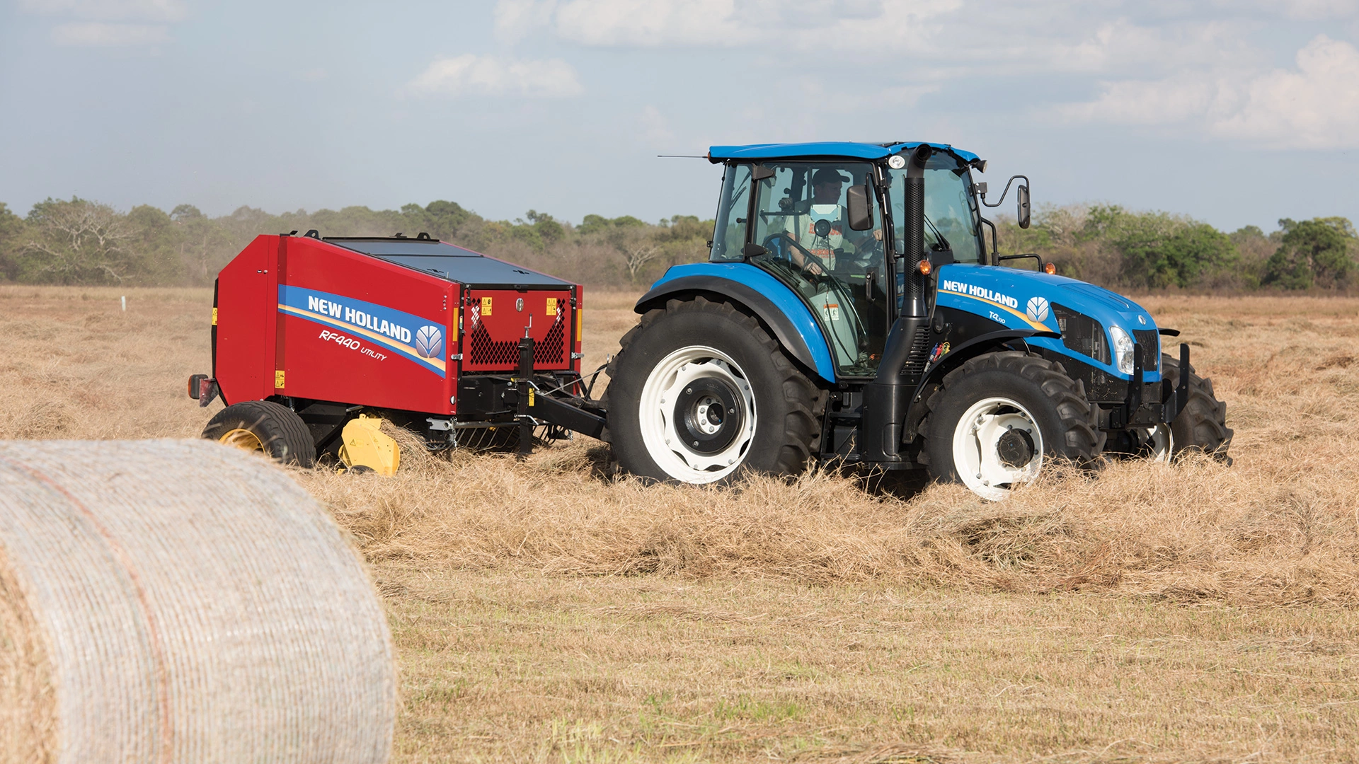 RF Fixed Chamber Round Baler pulled behind a New Holland tractor