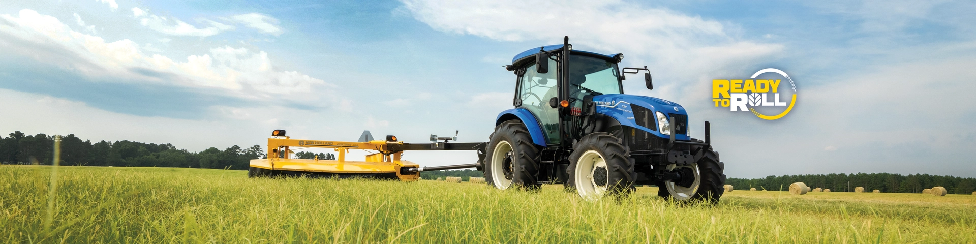 New Holland tractor pulls a disc mower in the field.