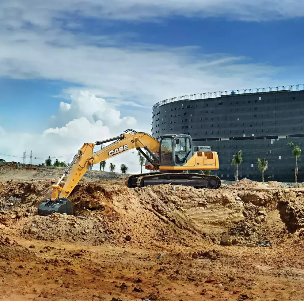 foto ao ar livre da escavadeira hidráulica da Case Construction realizando uma escavação na frente de uma grande construção elaborada por Oscar Niemeyer.