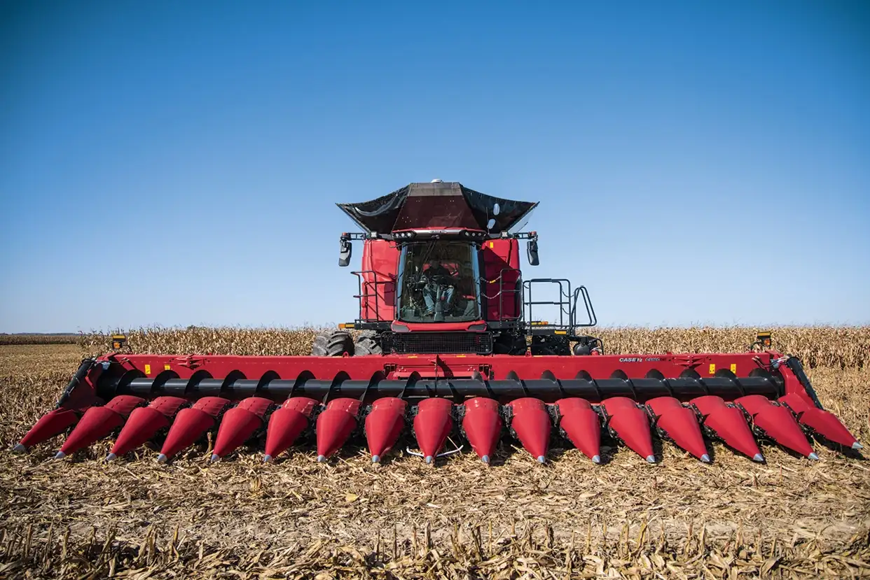 Case IH C500 series combine harvester with sharp front attachments parked in a cornfield under a clear blue sky. 