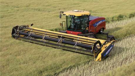 Windrower cutting hay in a field.