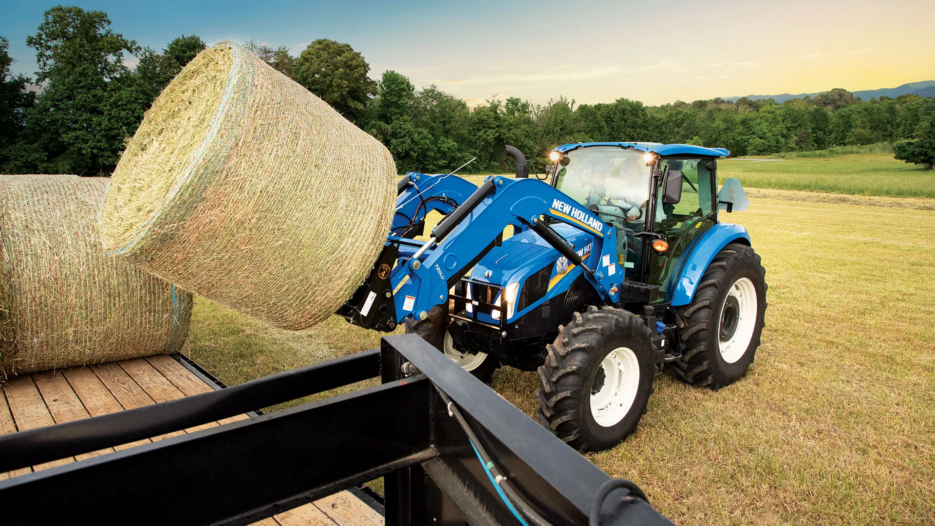 T5 Series tractor lifts a bale