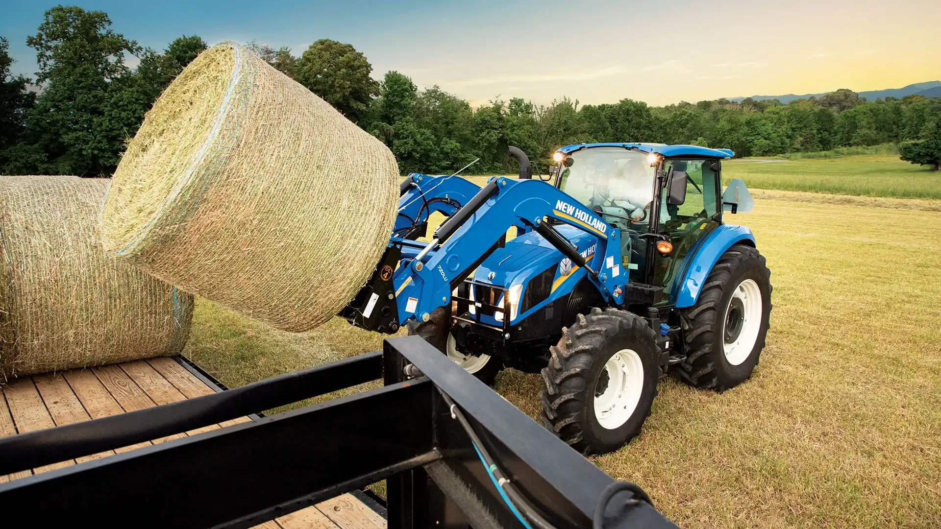T5 Series tractor lifts a bale