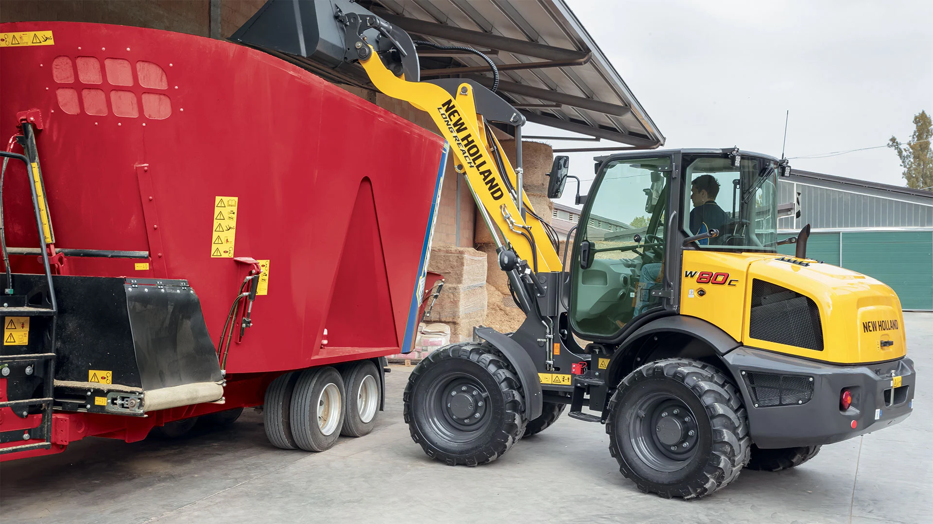 New Holland compact wheel loader in action, scooping up mixed soil on a construction site.